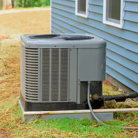 An outdoor air conditioning unit installed beside a blue house, connected to power and refrigerant lines for climate control efficiency.