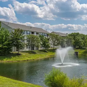 a fountain in the pond with a building in the background