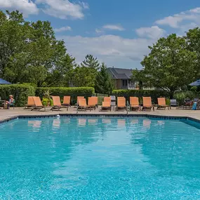 a swimming pool with chairs and umbrellas at the resort on a sunny day