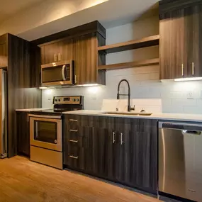 A modern kitchen with dark wood cabinets and stainless steel appliances.