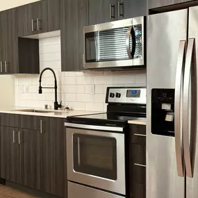 A modern kitchen with a stainless steel refrigerator and oven.