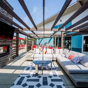 a patio with a couch and a coffee table in front of a fireplace