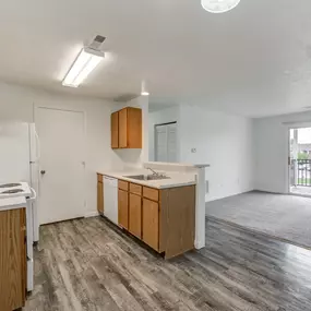 An empty kitchen and living room with a door to a balcony