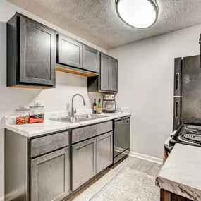 A kitchen with a black stove top oven and a white sink.