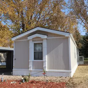An exterior view of a beige and white mobile home and a carport