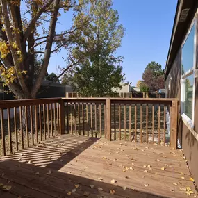 An exterior view of a brown deck that is attached to the mobile home from the perspective of the front door