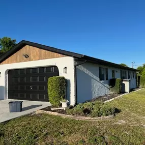 3 Brothers Painting & Home Improvements, LLC updated this home's exterior with modern light-gray stucco, black trim and garage door, and natural wood accents for a bold, clean, and contemporary curb appeal.