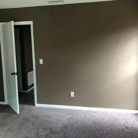 3 Brothers Painting & Home Improvements, LLC completed this room with rich brown walls, white trim, and plush carpeting. Natural light streams in through a large window, creating a warm, cozy space.