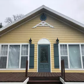 3 Brothers Painting & Home Improvements, LLC revitalized this home’s exterior with cheerful yellow siding, white trim, teal shutters, and a matching front door, creating a fresh, inviting curb appeal.