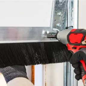 A homeowner installing an Xcluder garage door seal for rodent prevention