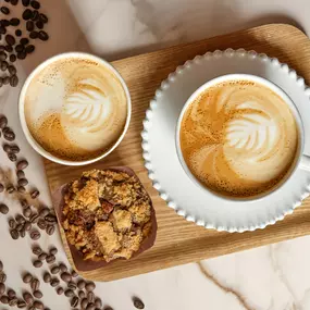two lattes with beautiful foam art and a chocolate muffin