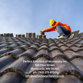 Roofing contractor installing ceramic tiles on a sloped residential roof under clear skies.