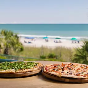 Pizzas on display at Reel Food & Drink with beach view in the distance