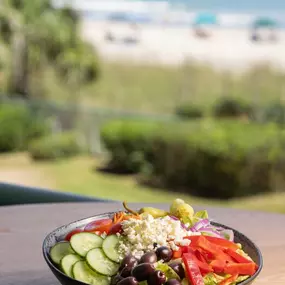 A salad on display at Reel Food & Drinks with a beach view in the distance