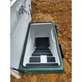 Interior view of a fiberglass tornado shelter showing molded seating, cross ventilation, and non-skid steps. Built for comfort and safety.