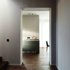 Reduziert, klar und atmosphärisch: Der Blick durch den Flur in den Wohnbereich offenbart ein Zusammenspiel aus hochwertigen Materialien, gedeckten Farben und architektonischer Präzision. Natürliches Licht und ausgewählte Details verleihen dem Raum Ruhe und Tiefe.