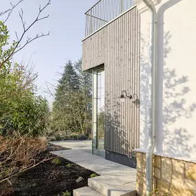Architektonisches Detail an der Schnittstelle zwischen Bestand und Anbau: Die Kombination aus Putz, Naturstein, Holzverschalung und Metall schafft ein harmonisches Gesamtbild mit handwerklicher Präzision.