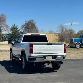 Rear three-quarter view of a white Chevrolet Silverado HD truck parked outdoors. The focus is on the deeply tinted rear windshield, offering maximum privacy and a sleek appearance.