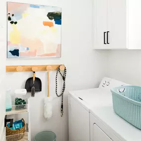 a small laundry room with a washing machine and a painting on the wall