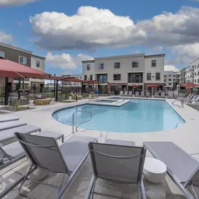 swimming pool with lounge chairs and umbrellas in front of a building