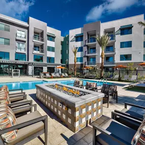 a swimming pool with a fire pit in front of an apartment building
