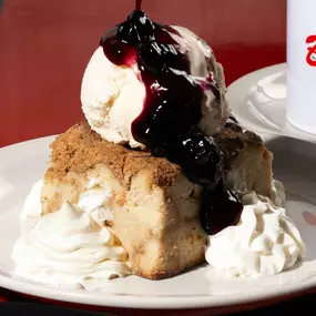 Homemade bread pudding topped with vanilla ice cream and berry sauce at Bambinelli’s Pizza & Pasta. A sweet finish from one of the top Italian restaurants in Atlanta—perfect after pasta in Atlanta or pizza near me.