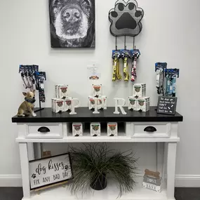 Playtime Pet Resort Exeter’s boutique retail setup includes dog treats, leashes, and accessories, all arranged on a modern white and black console with charming decor.