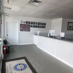 Bright, open lobby with a check-in counter and a gallery wall showcasing pet photos at Playtime Pet Resort Windham. The clean flooring and layout emphasize professionalism and pet-friendly design.