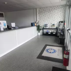 The Windham location lobby features a clean reception counter and a stylish corner retail display with treats, leashes, and decor. Dog-themed wallpaper adds a playful and welcoming touch.