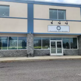Front view of the Playtime Pet Resort Windham facility, with modern stonework, large windows, and clearly visible signage above the entrance.