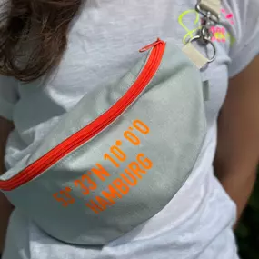 Canenya - Raumdesign für Kinder Bauchtasche mit neonorangefarbenem Reißverschluss und Hamburg-Koordinaten. Nachhaltig gefertigt, praktisch für Stadt, Reisen und Freizeit. Handgefertigtes Accessoire mit auffälligem, trendigem Design.