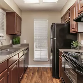 A kitchen with brown cabinets and black appliances.