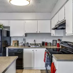 A kitchen with white cabinets and a black fridge
