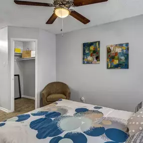 A bedroom with a bed, a chair, and a ceiling fan