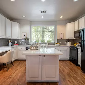 A kitchen with a black refrigerator and white cabinets.