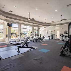 A gym with a variety of equipment including treadmills, elliptical machines, and weights.