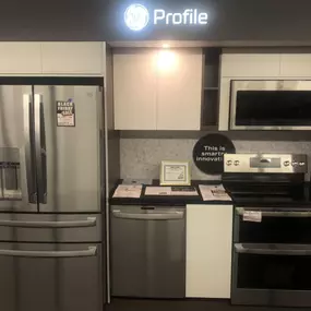 A full GE Profile kitchen package display including refrigerator, dishwasher, range, and over-the-range microwave.