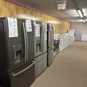 A look down one of the showroom aisles, showcasing refrigerators, washers, and dryers in a neatly organized display.