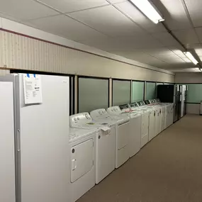 A showroom section featuring an extensive selection of top-loading and front-loading washers and dryers.