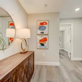 A decorated hallway at The Groves at Lake Ella leads to the bedrooms, featuring a large mirror and warm accents.