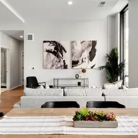 A modern living room with a grey sofa, a wooden table, and a large abstract painting on the wall