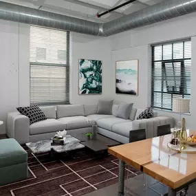A modern living room with a grey sofa, a green ottoman, a wooden coffee table, and a painting on the wall