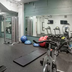 A gym with a variety of equipment including a treadmill, exercise balls, and weight machines