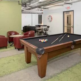A pool table in a room with a clock on the wall