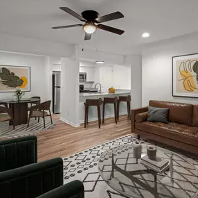 A living room with a brown couch, a dining table with chairs, and a ceiling fan.