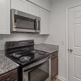 A kitchen with a stove, microwave, and refrigerator.