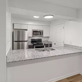 A kitchen with a granite countertop and stainless steel appliances.