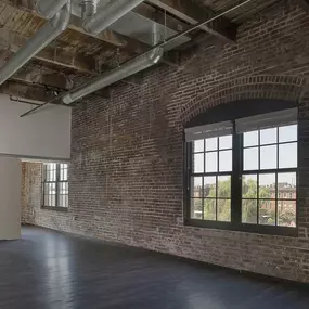 A large empty room with a brick wall and a large window.