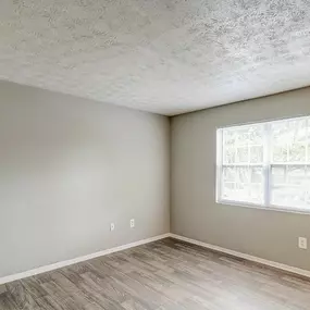 A room with a window and wooden flooring.