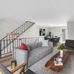 A living room with a grey couch, a coffee table, and a staircase
